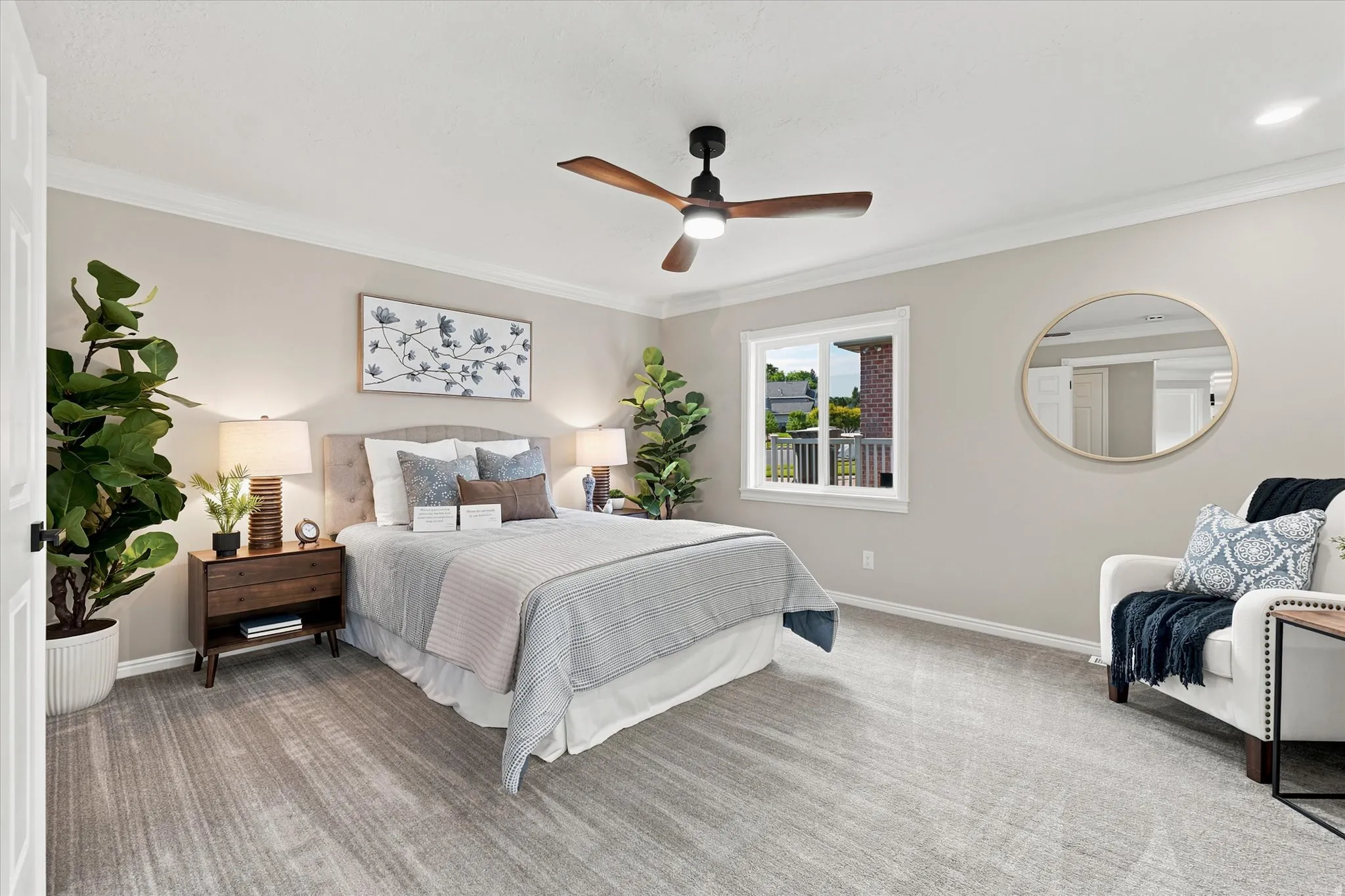 Spacious bedroom featuring plush gray carpeting, crown molding, a ceiling fan with integrated lighting, a large window, and a built-in closet with sliding doors