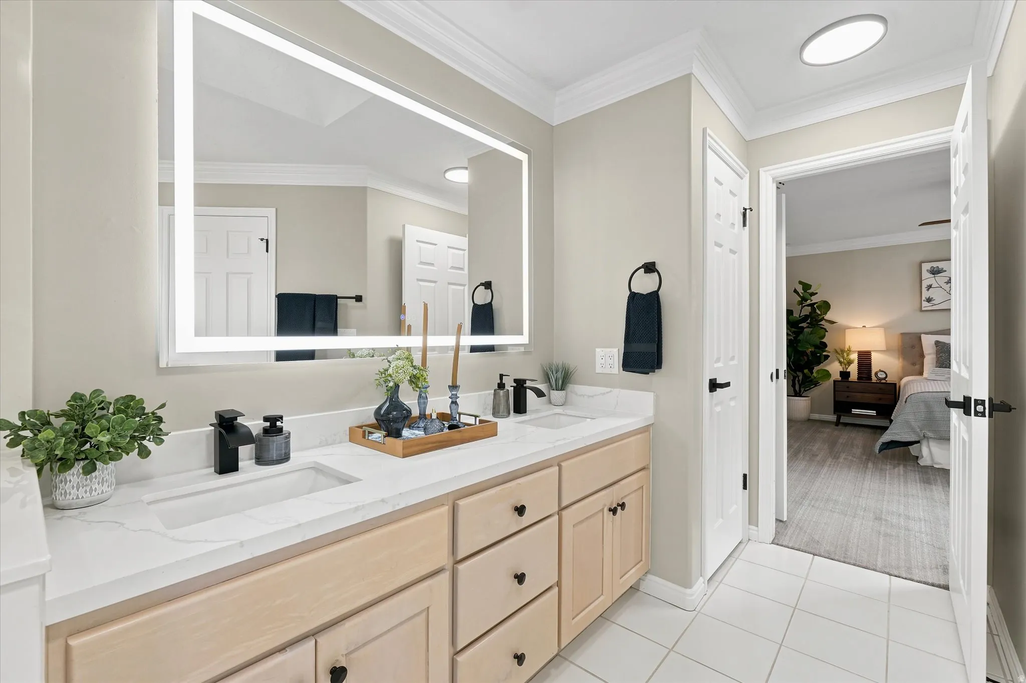 Double vanity featuring integrated sinks, light wood-finish cabinetry, and matte black fixtures