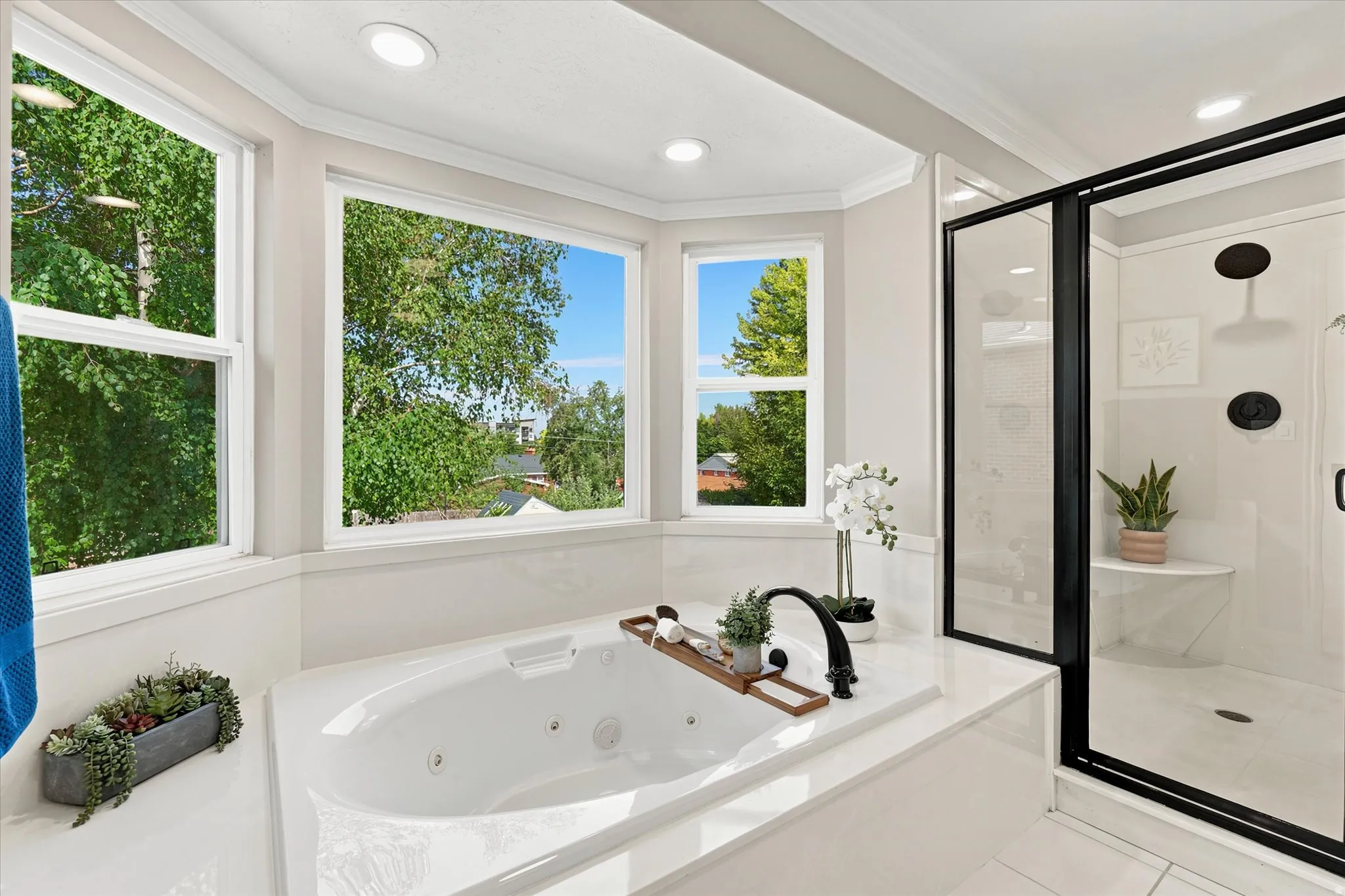 Bathroom featuring a built-in jetted tub, expansive window array, and an enclosed shower with matte black fixtures and a built-in bench