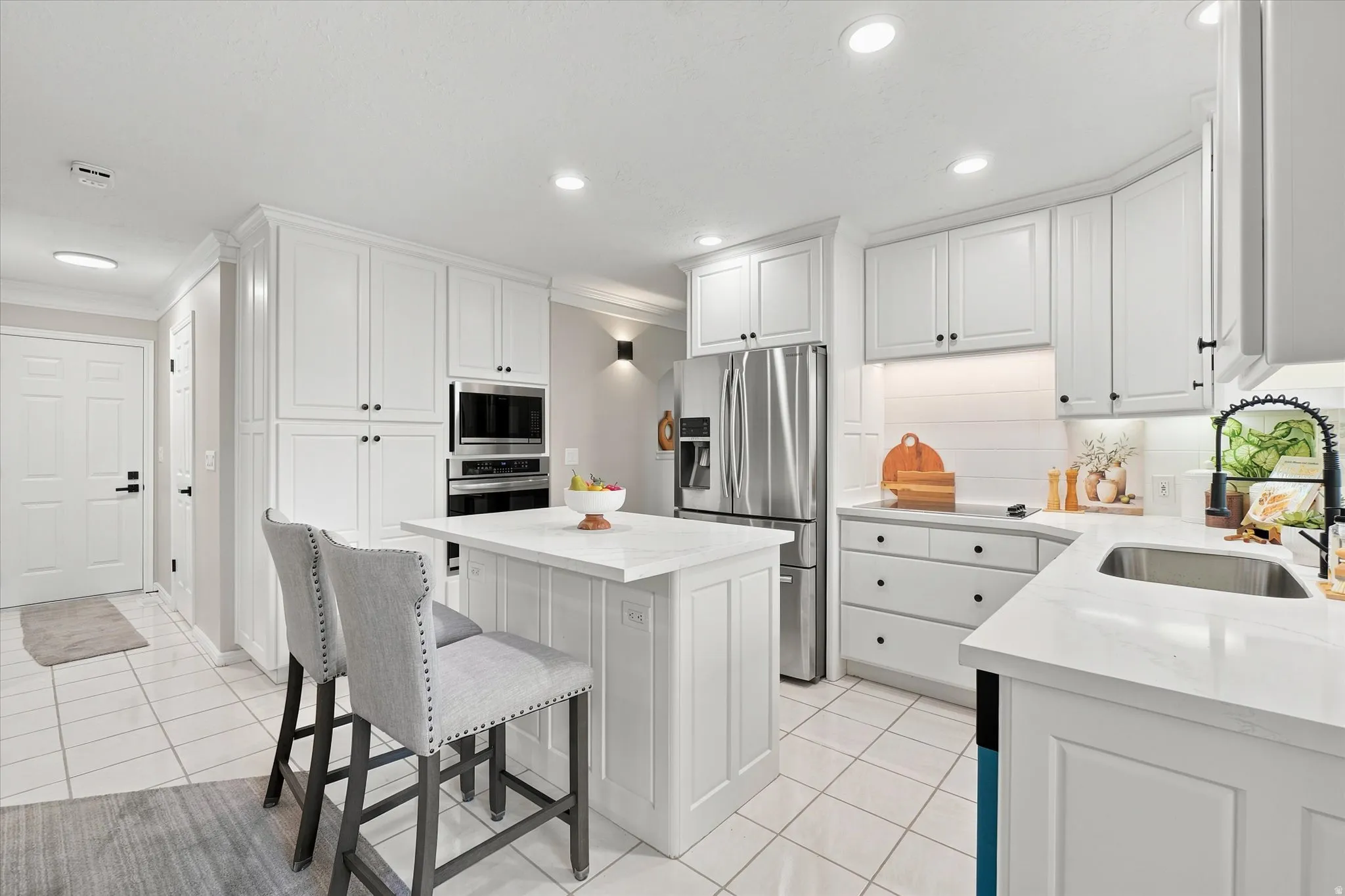 Modern kitchen featuring white shaker cabinetry with black hardware, stainless steel appliances, and an undermount sink