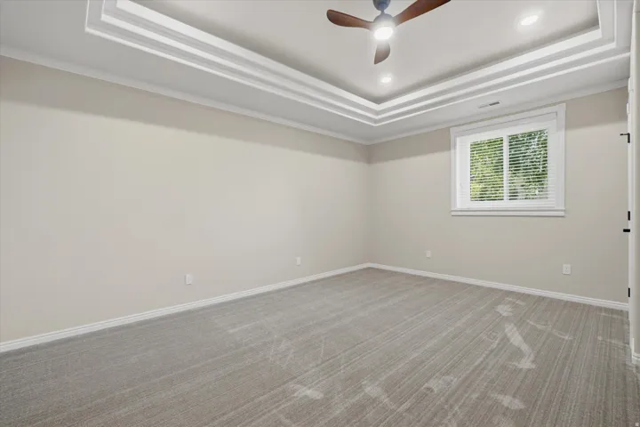 Neutral tone walls with white baseboards frame a spacious room featuring patterned carpeting