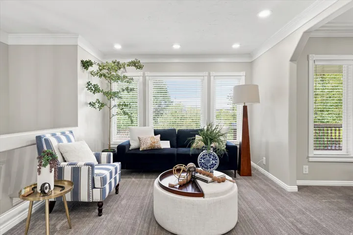 Living area featuring a triple window arrangement, crown molding, recessed lighting, carpet flooring, and a cased opening
