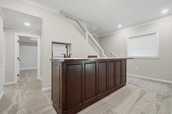 Built-in wet bar featuring dark wood cabinetry, a light-toned countertop, and a matte black faucet