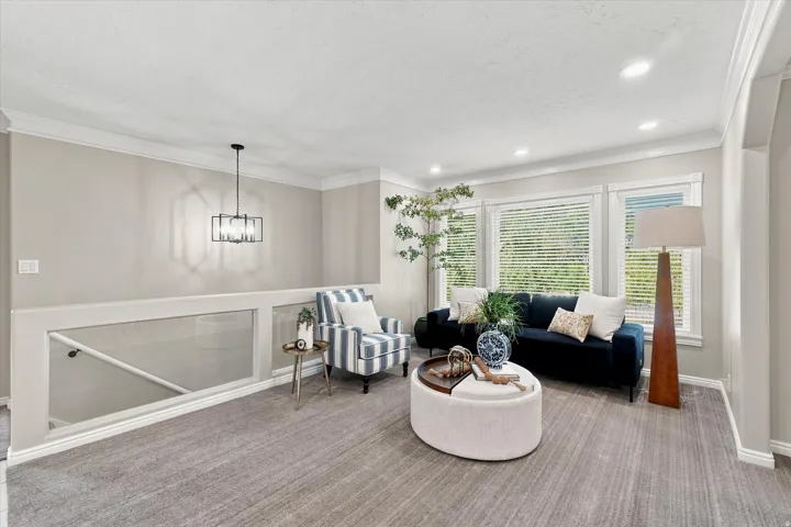 Upper-level lounge area featuring light gray wall paint, recessed lighting, and crown molding