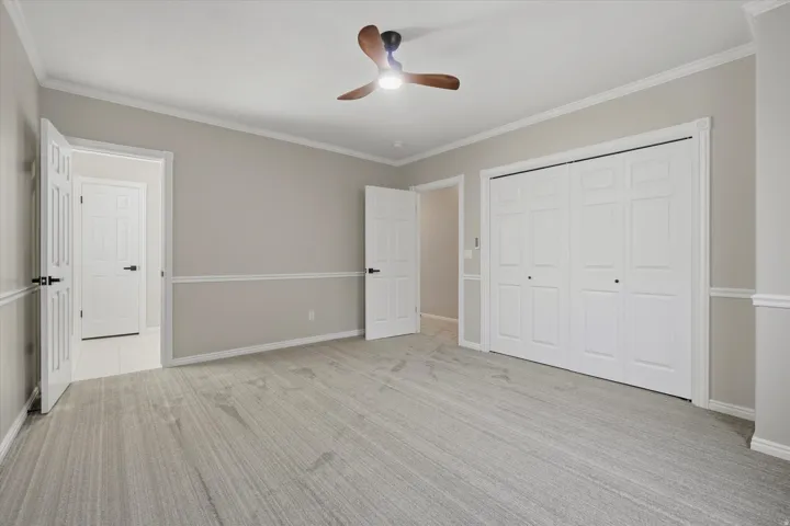 Spacious room featuring light grey wall paint, white trim, and crown molding