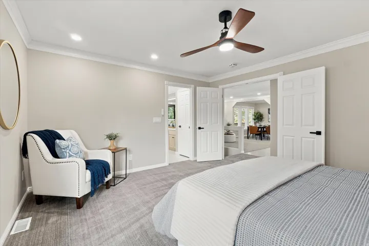 Spacious bedroom with light gray wall paint, recessed lighting, and a contemporary ceiling fan