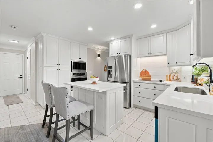 Modern kitchen featuring white shaker cabinetry with black hardware, stainless steel appliances, and an undermount sink