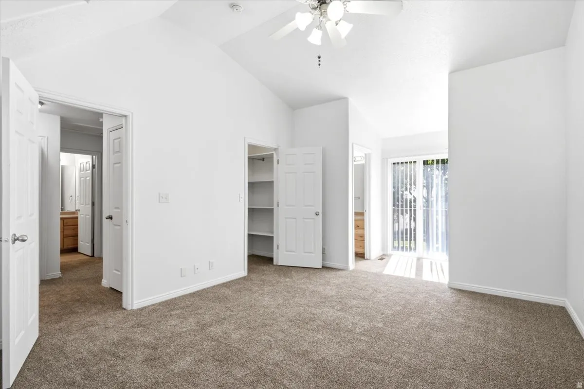 Carpeted room featuring a vaulted ceiling and ceiling fan