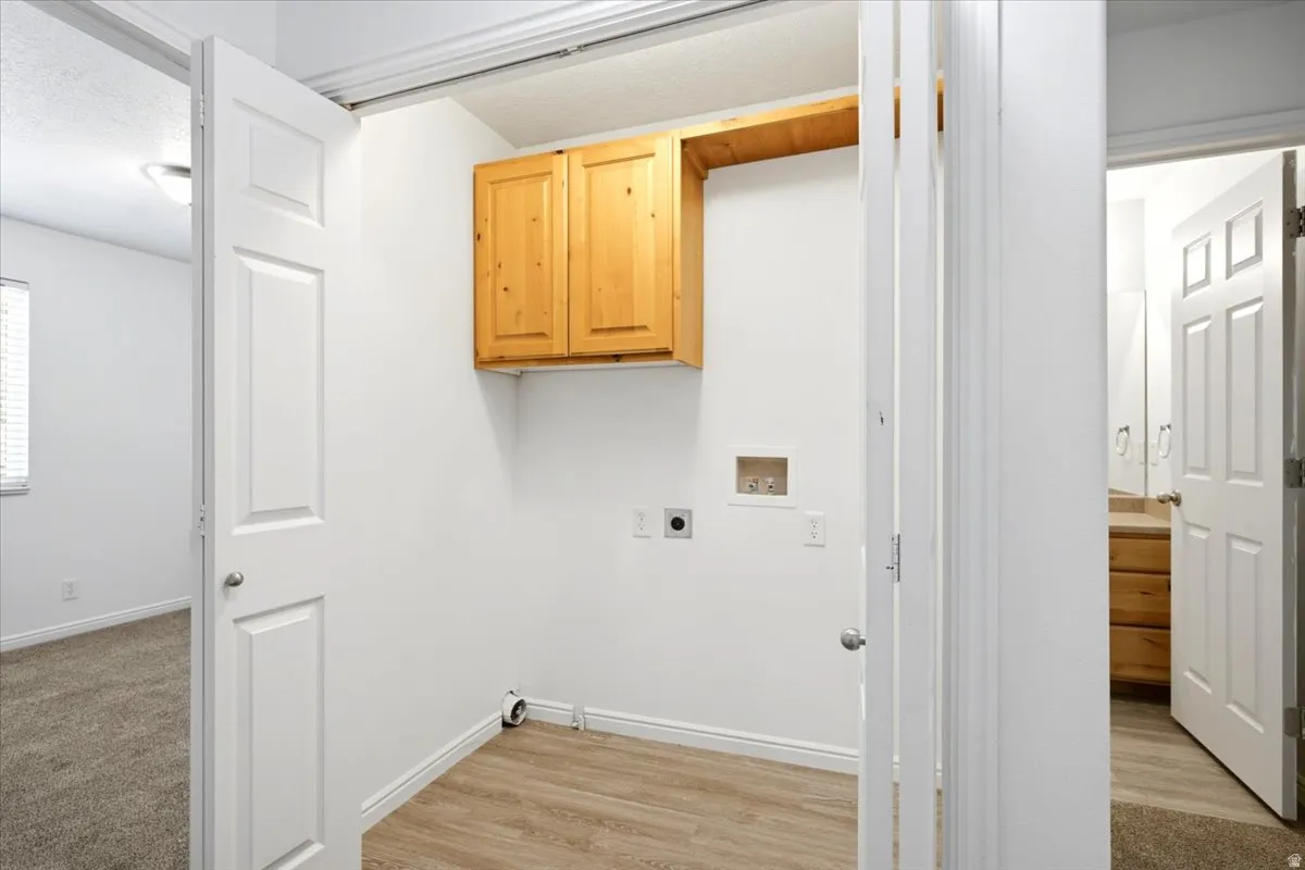 Dedicated utility space featuring wood-finish flooring and integrated cabinetry