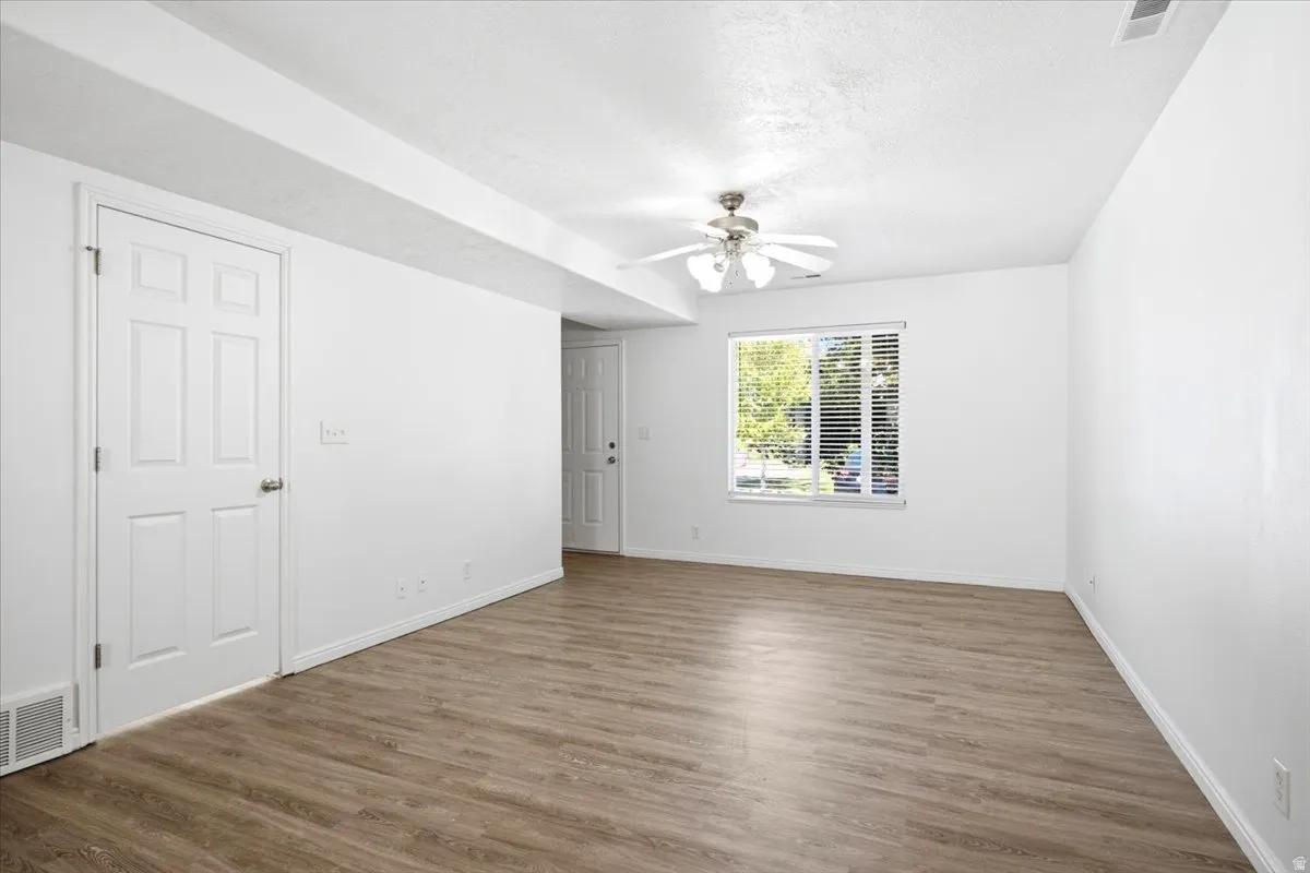 Spacious room with wood-finish flooring and bright white walls