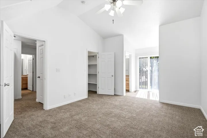 Carpeted room featuring a vaulted ceiling and ceiling fan