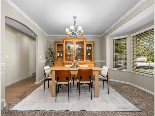 Formal dining space featuring crown molding, neutral wall tones, and a bay window