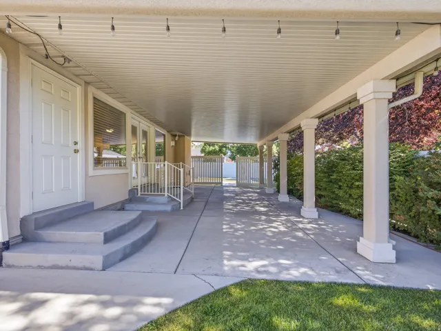 Massive covered patio featuring an expansive concrete surface, support columns, and string lighting