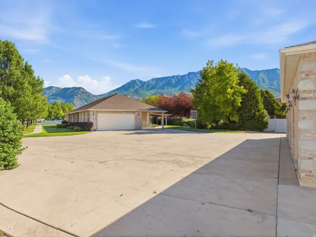 Expansive concrete parking pad bordered by mature trees and mountain scenery