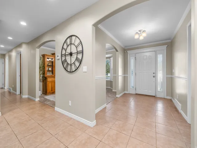 Tiled entryway featuring a white paneled door with sidelights, overhead light fixture, and arched doorways