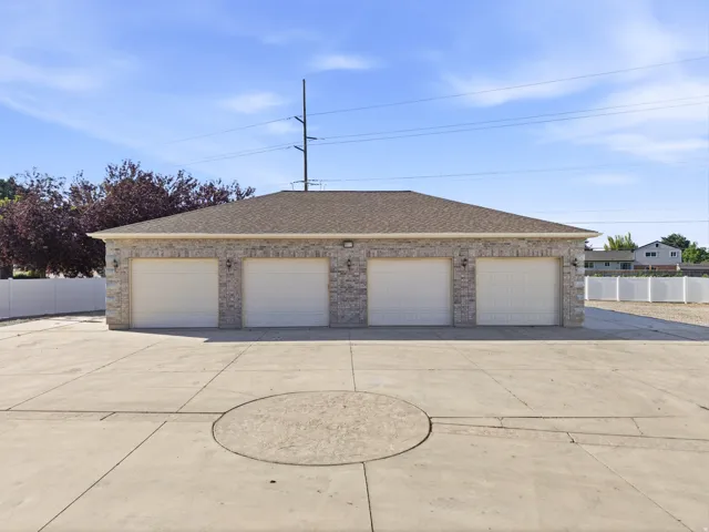 Four-bay/ 8 car garage structure featuring stone veneer siding, a shingle roof, and individual garage doors