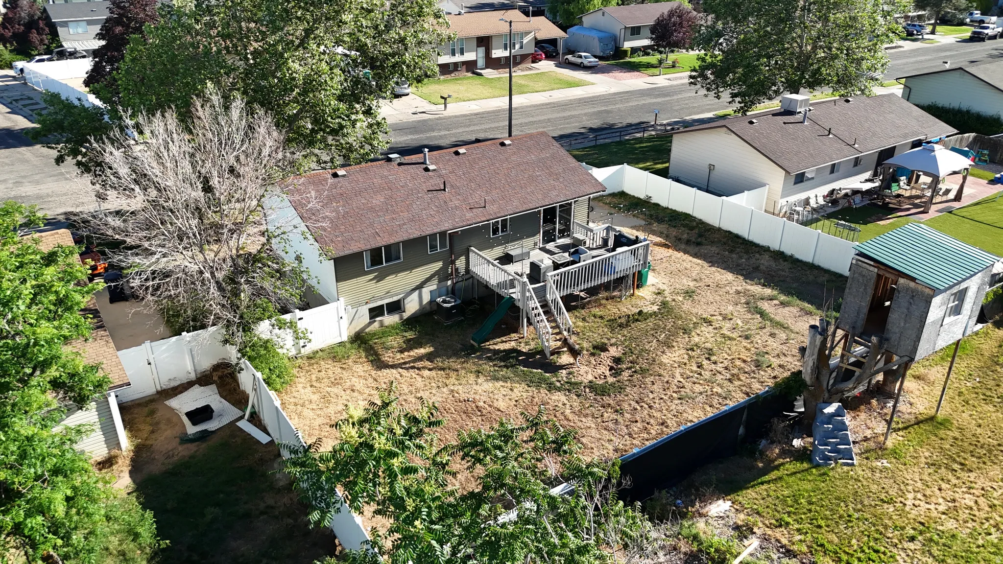 Expansive backyard with a large wood deck and white vinyl fence