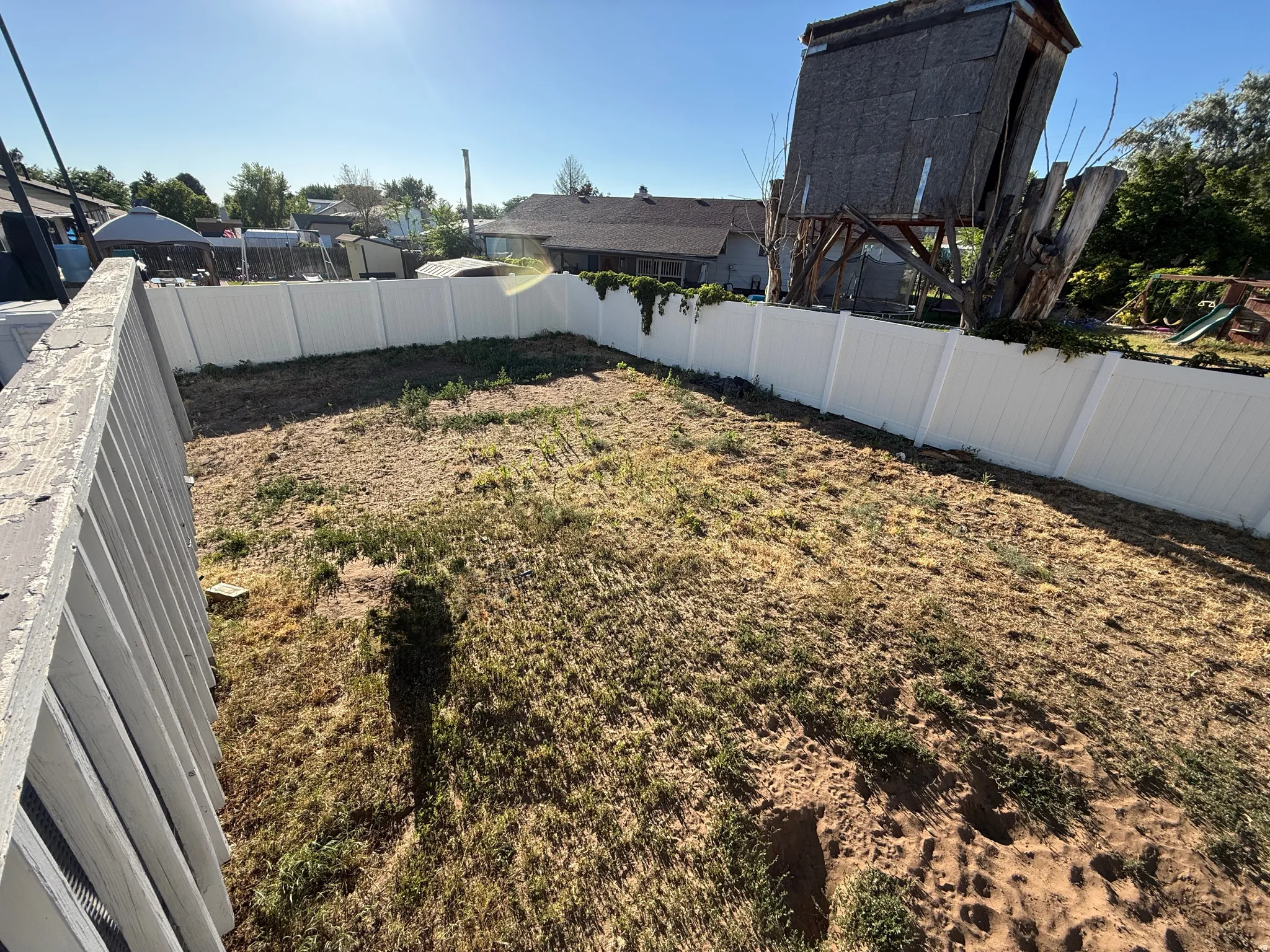 Spacious backyard area featuring a white privacy fence, providing a defined property boundary