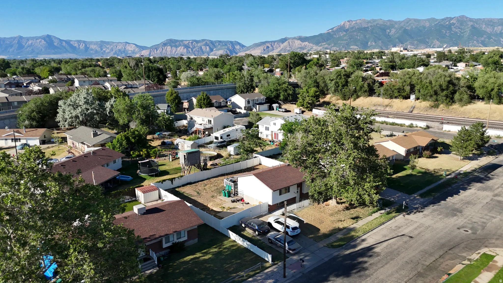 Expansive neighborhood setting featuring a variety of residential structures with mature trees and mountain ranges in the background