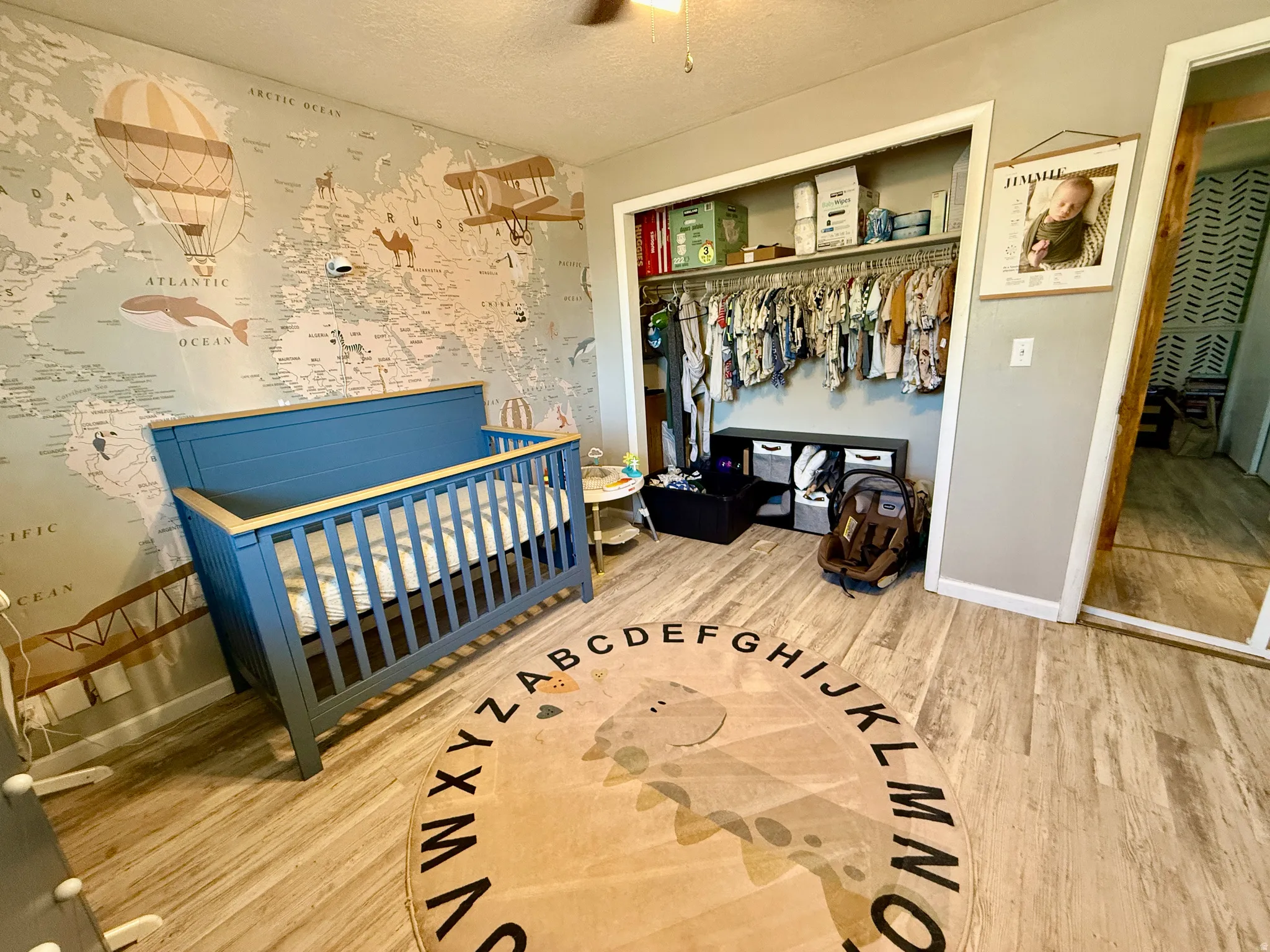Bedroom featuring wood-finish flooring, a patterned accent wall, and a built-in closet with shelving and hanging storage