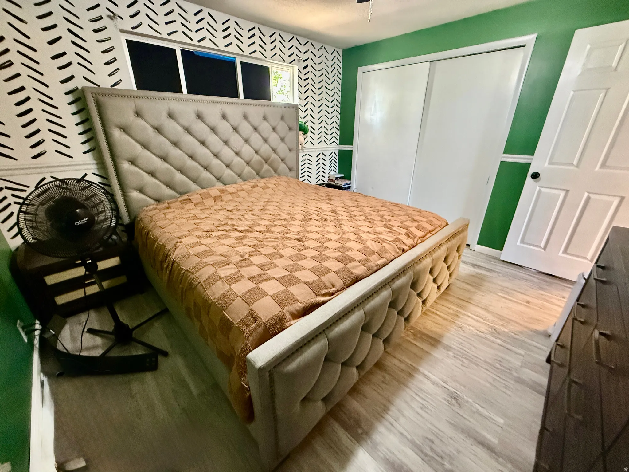 bedroom featuring wood-finish flooring, white paneled door, and sliding closet doors