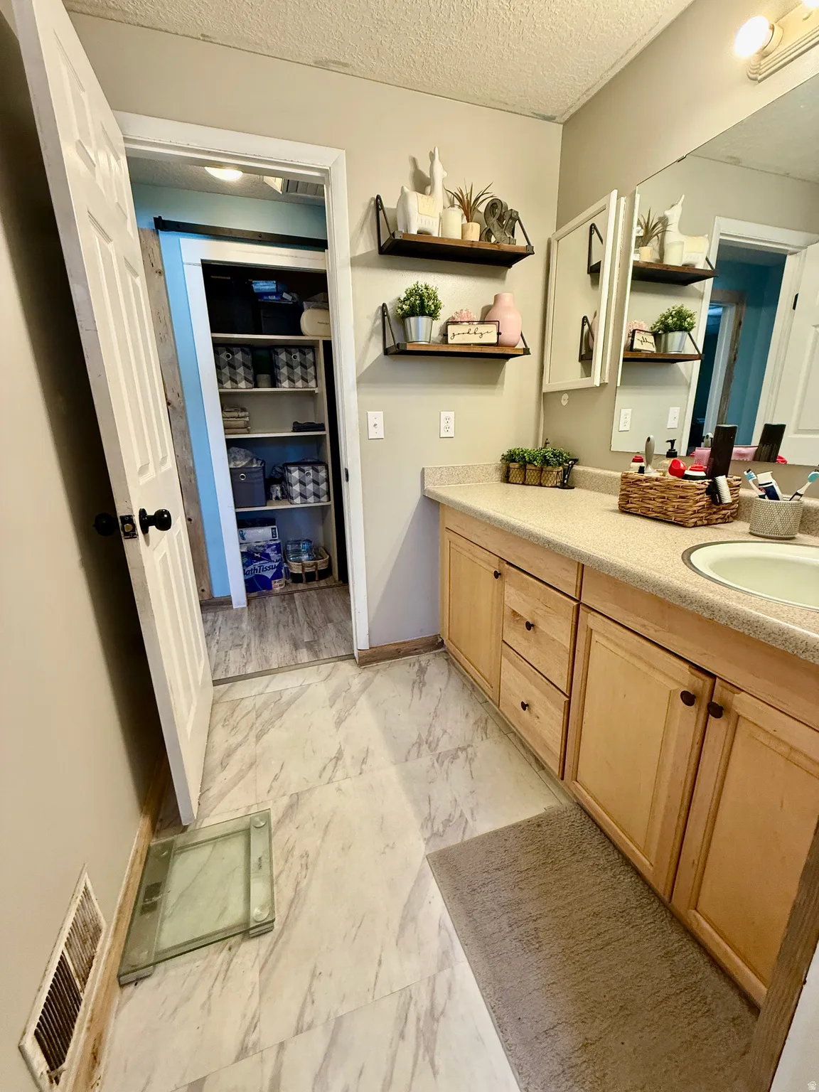 Bathroom vanity featuring light-toned wood cabinetry and a cream-colored countertop with and access to master bedroom