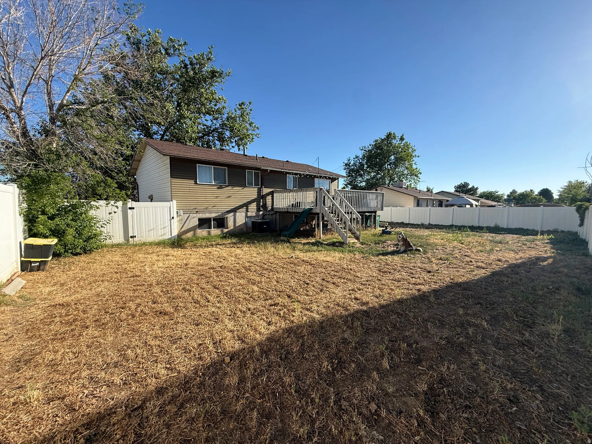 backyard featuring a wood deck, white vinyl fencing