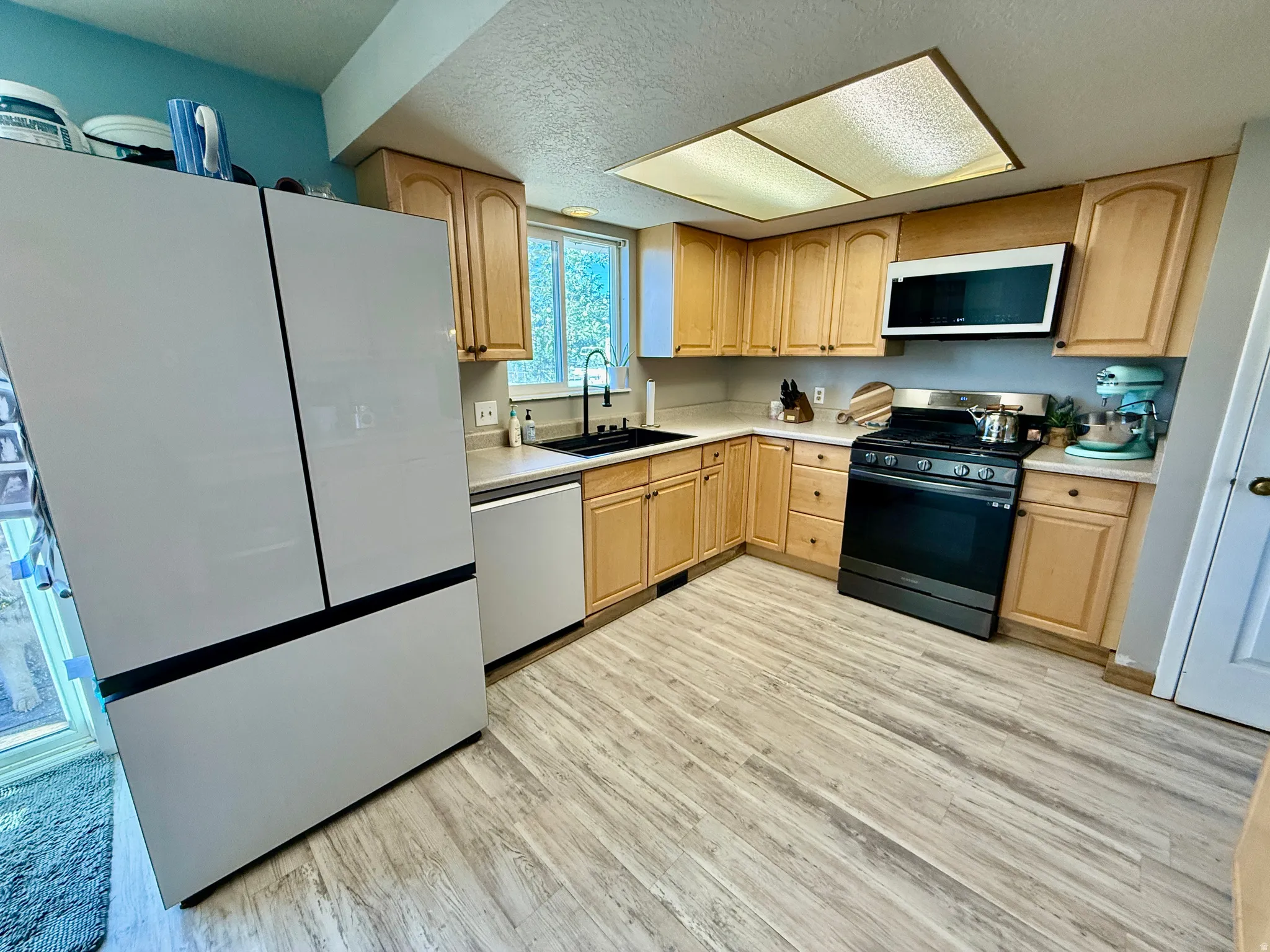 Kitchen featuring wood-finish flooring, light wood cabinetry, and new sink