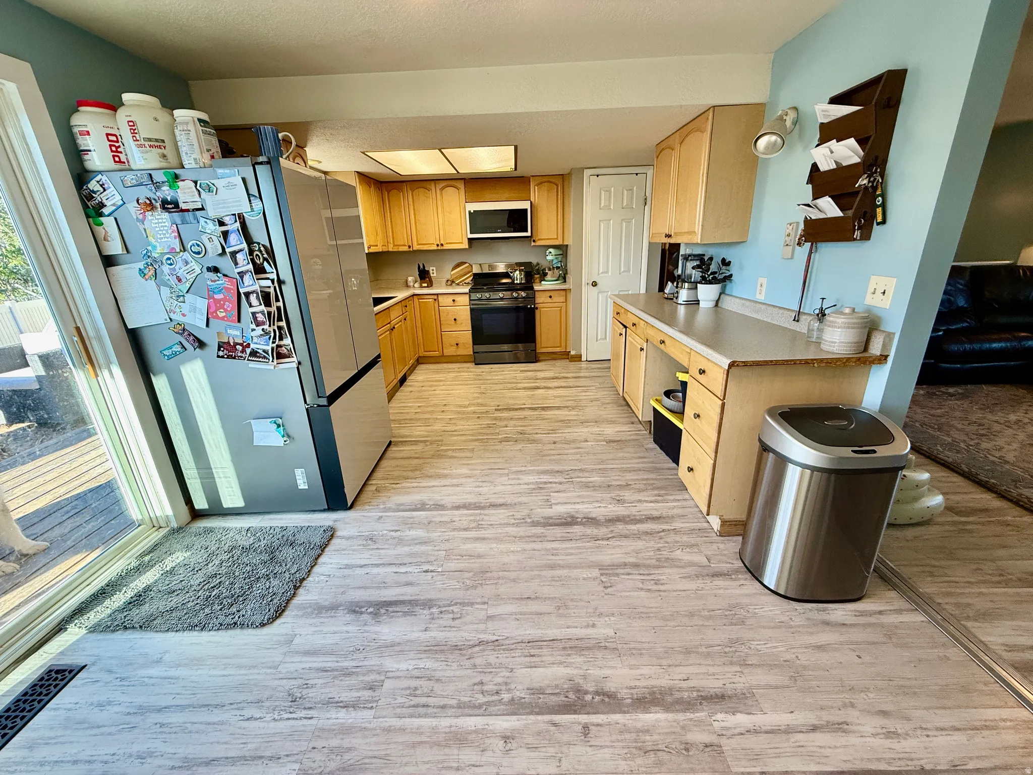 Kitchen featuring wood-finish flooring, lots  of cabinetry, and light-colored countertops
