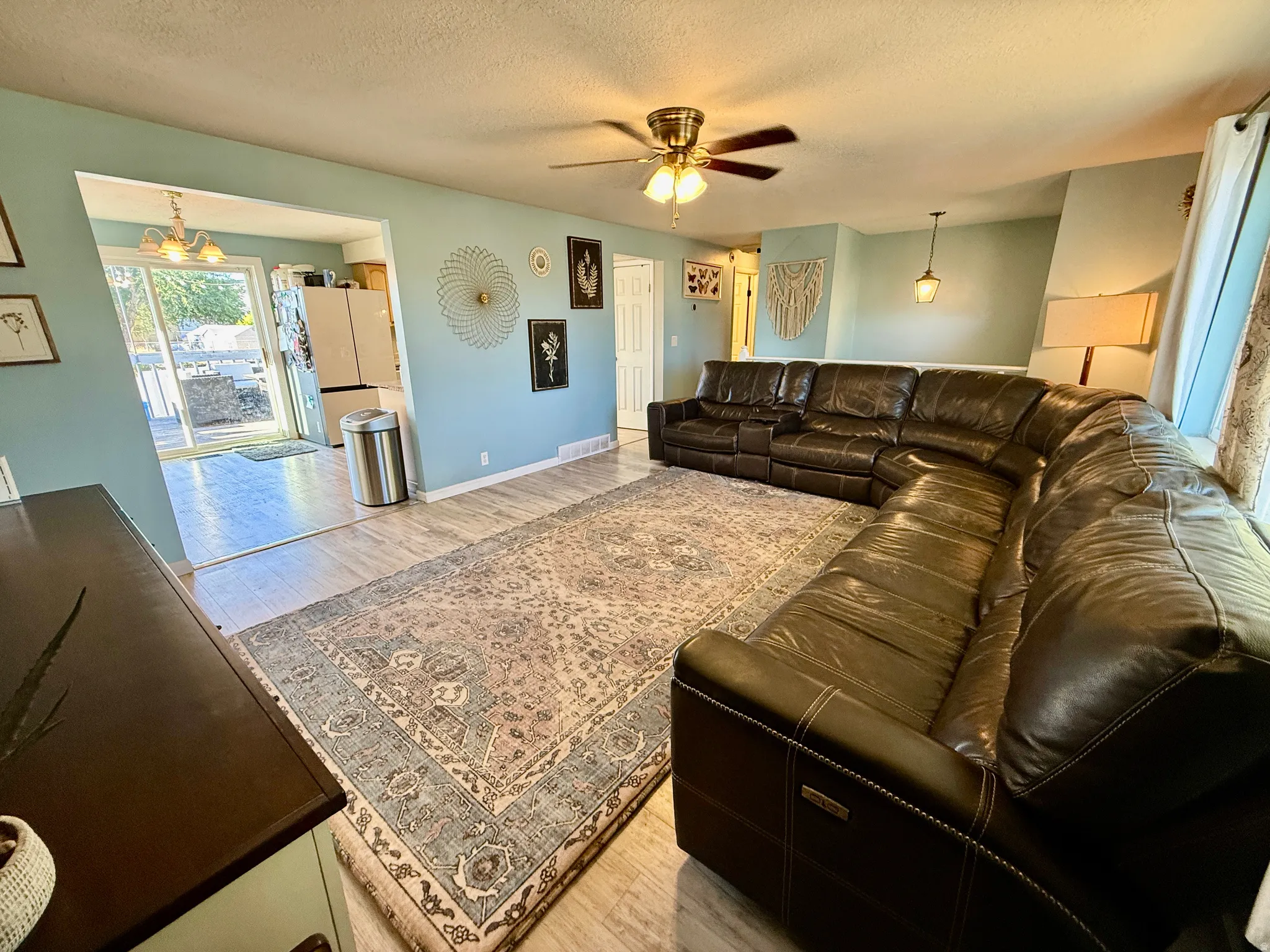 Spacious living area featuring light-toned walls and wood-finish flooring