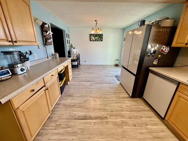 Kitchen featuring wood-finish flooring, light wood cabinetry, and neutral countertops