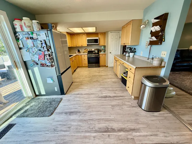 Kitchen featuring wood-finish flooring, lots  of cabinetry, and light-colored countertops