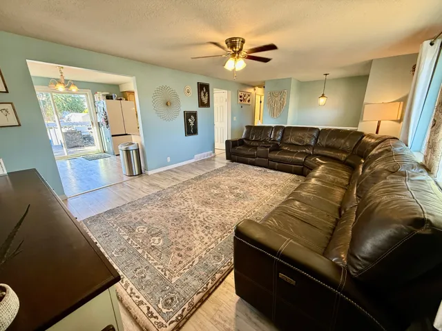 Spacious living area featuring light-toned walls and wood-finish flooring