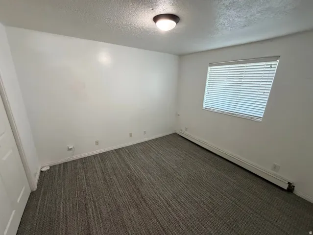 Room featuring textured carpet flooring, white walls, and a window with blinds