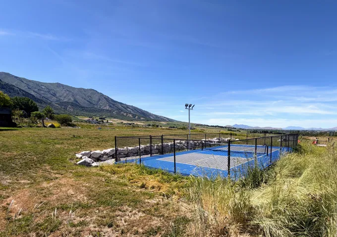 Outdoor sports court with blue surfacing, surrounded by a black chain-link fence