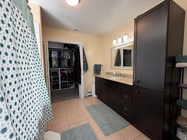 Bathroom featuring a dark wood-finish vanity with an integrated sink and light granite-finish countertop