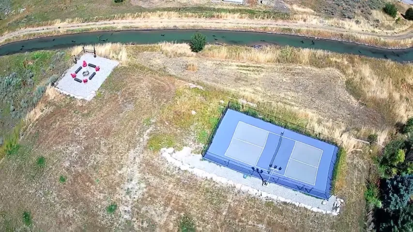 Outdoor amenities featuring a dedicated pickleball court and a gravel fire pit area
