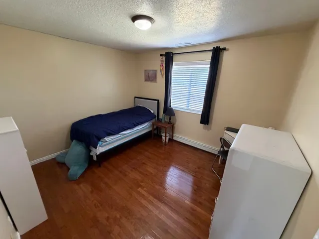 Room featuring wood-finish flooring, neutral wall tones, and a window with blinds
