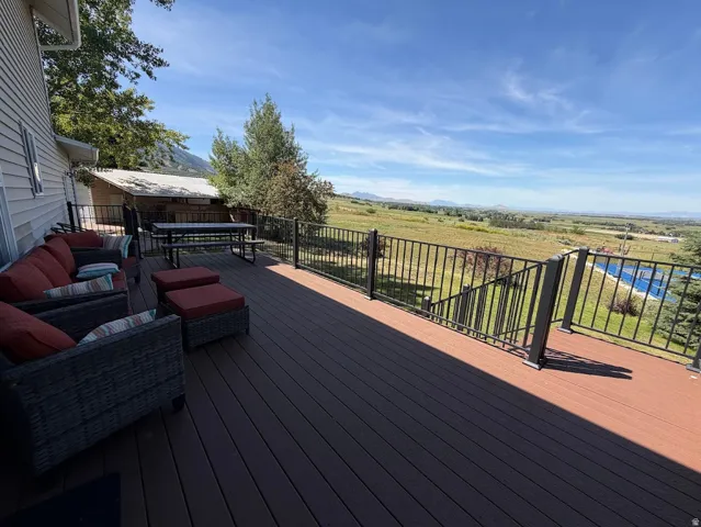 Spacious outdoor deck featuring composite decking and black metal railings, offering expansive pastoral scenery