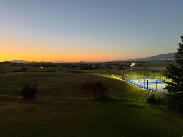 Private outdoor sports court with overhead illumination, set against a backdrop of distant mountains