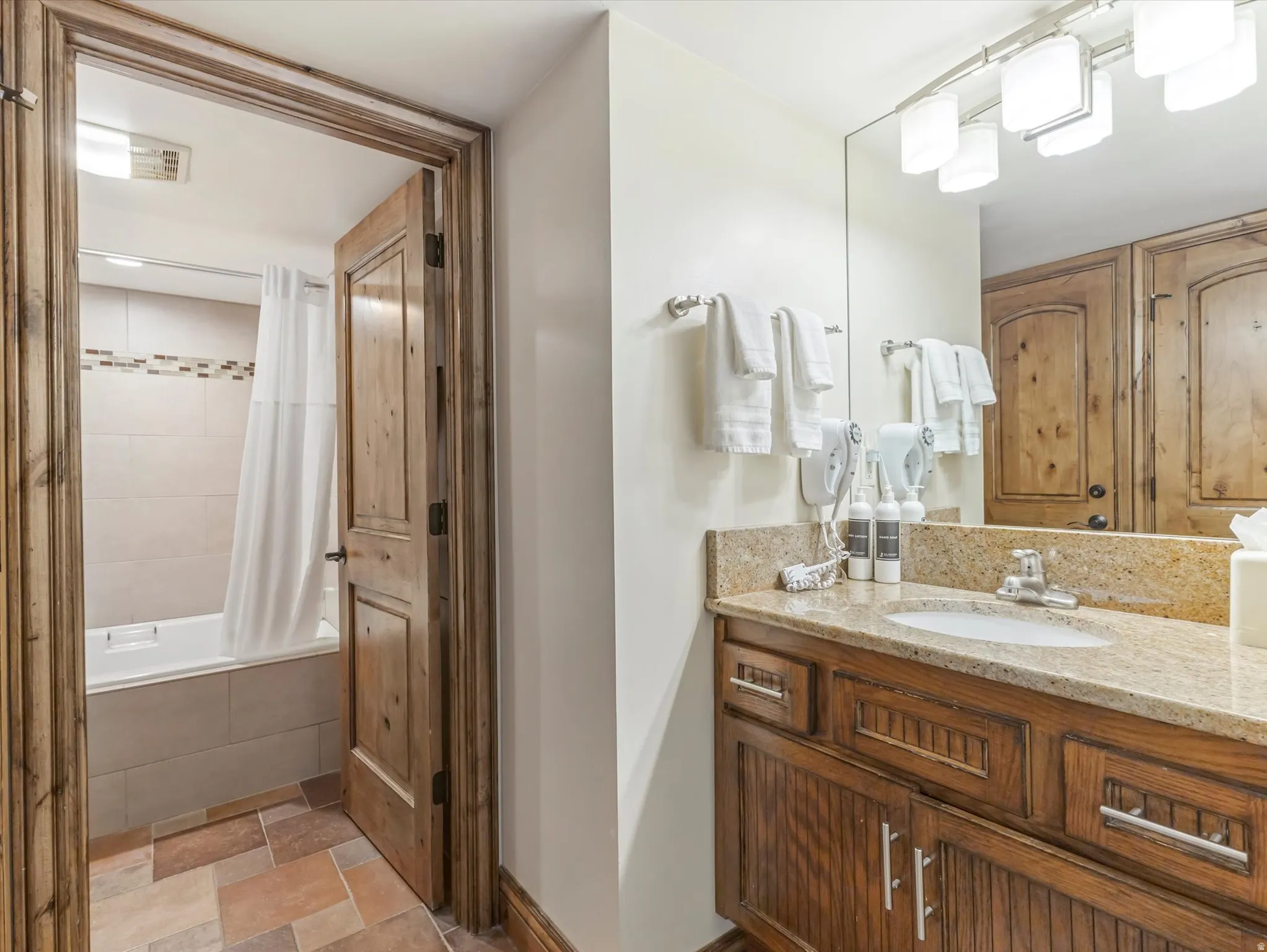 Bathroom featuring a wood-finish vanity with a stone countertop and an undermount sink
