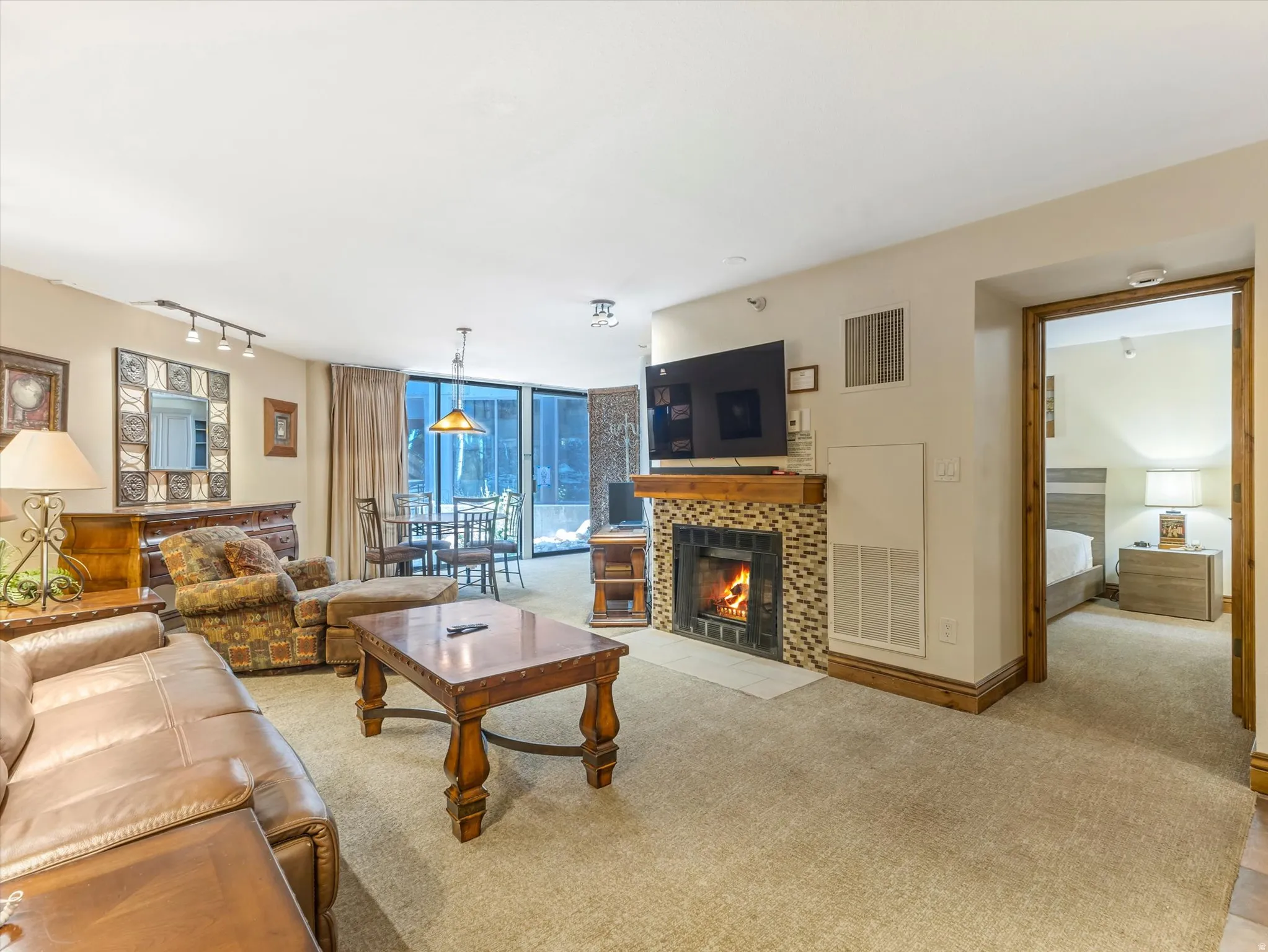 Living area featuring a stone tile fireplace with wood mantel, carpeted flooring, and direct access to an outdoor space via sliding glass doors