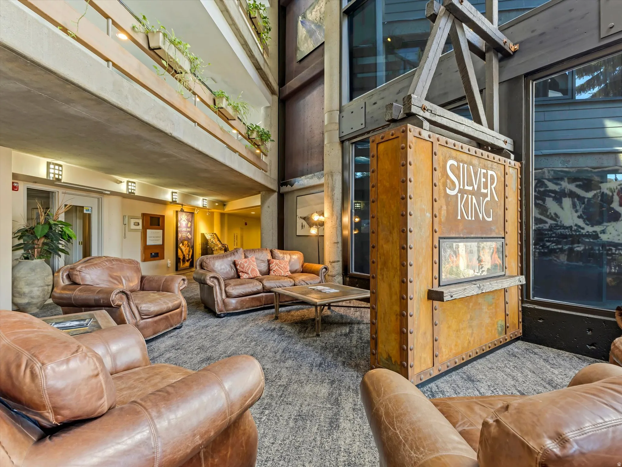 Spacious common area featuring an industrial-inspired design element, tall windows, multi-level balconies with planters, and recessed lighting