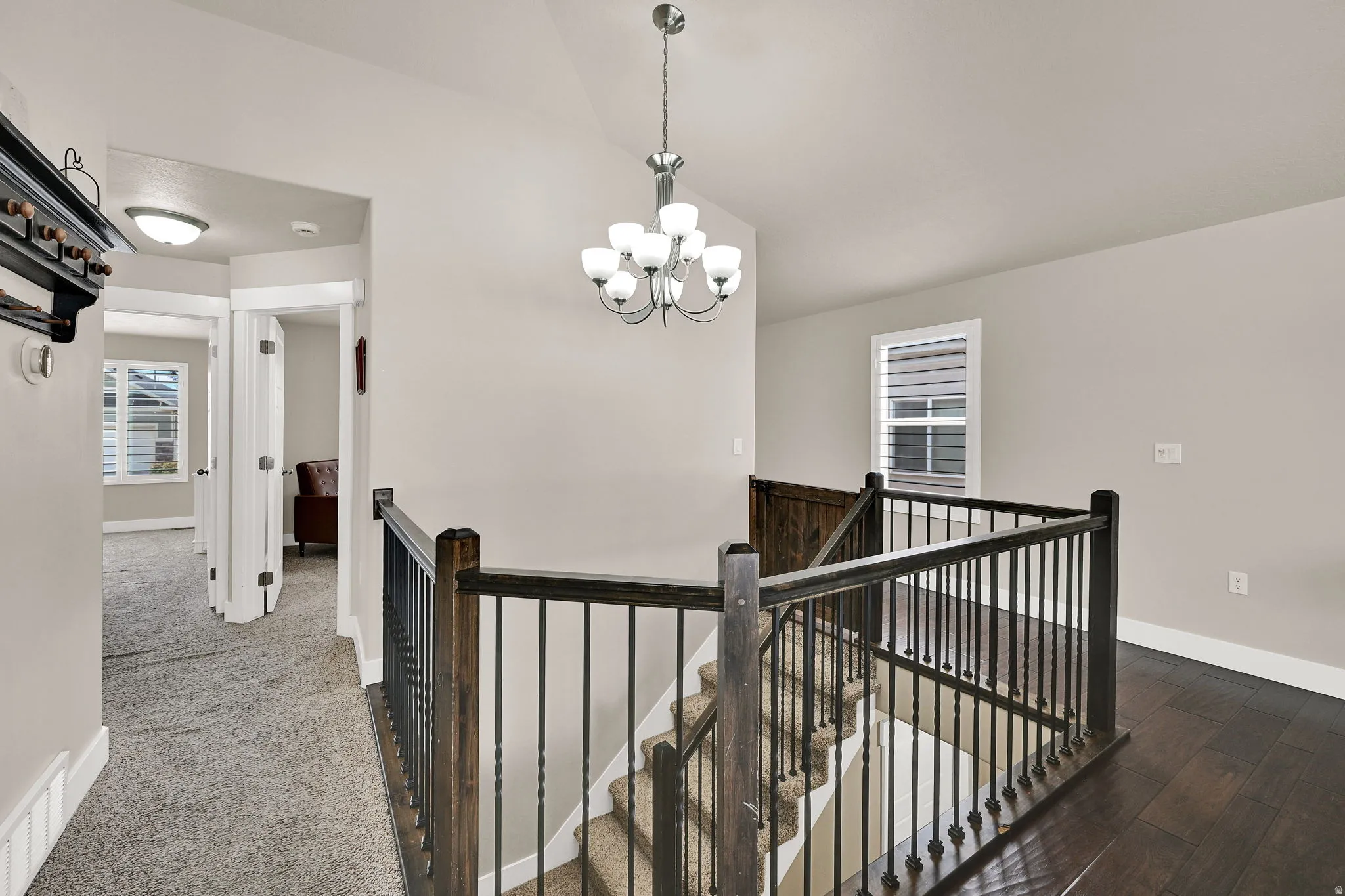 Staircase with dark wood newel posts and railings, featuring black wrought iron balusters