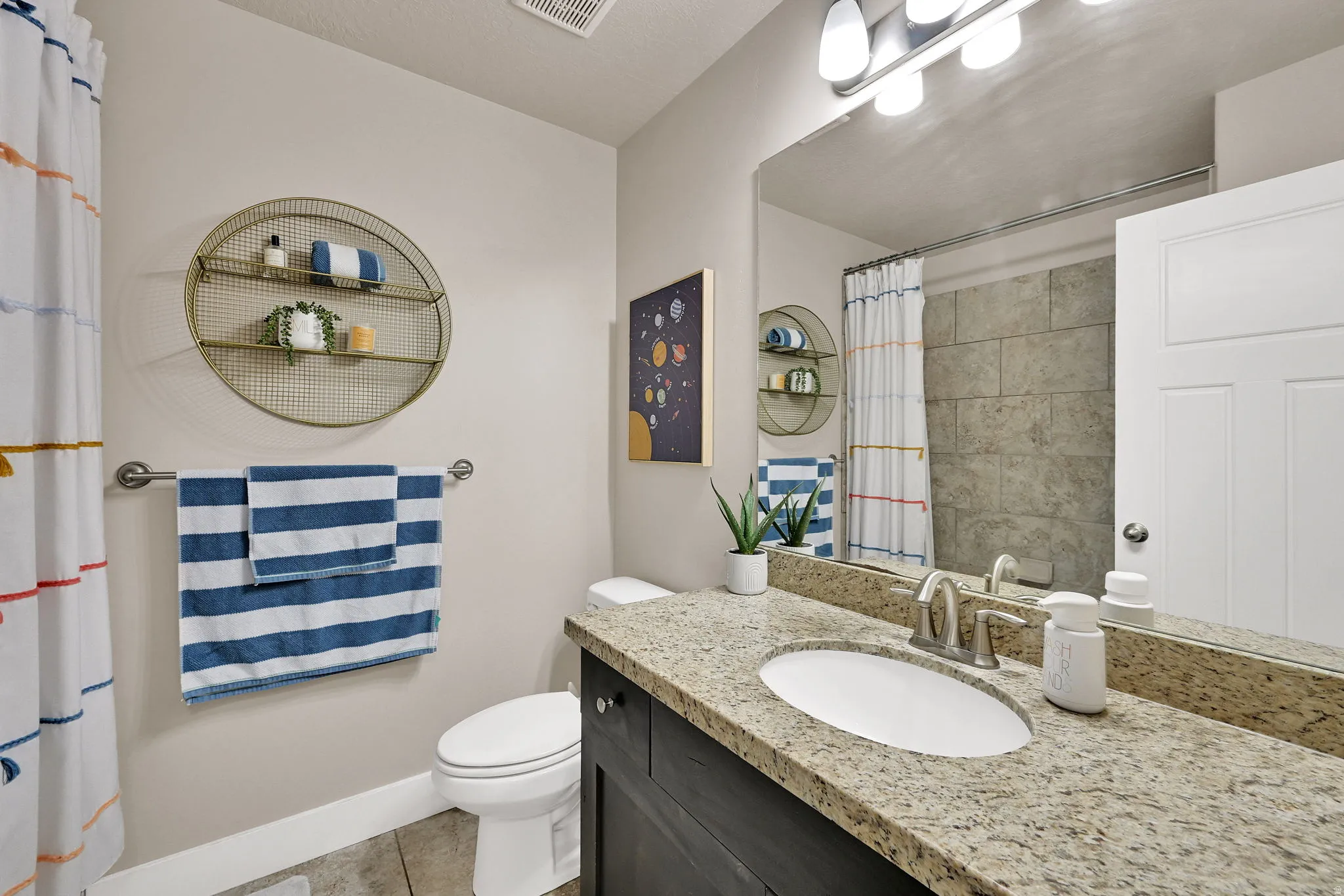 Bathroom featuring a vanity with a light-colored granite countertop, undermount sink, and brushed nickel faucet