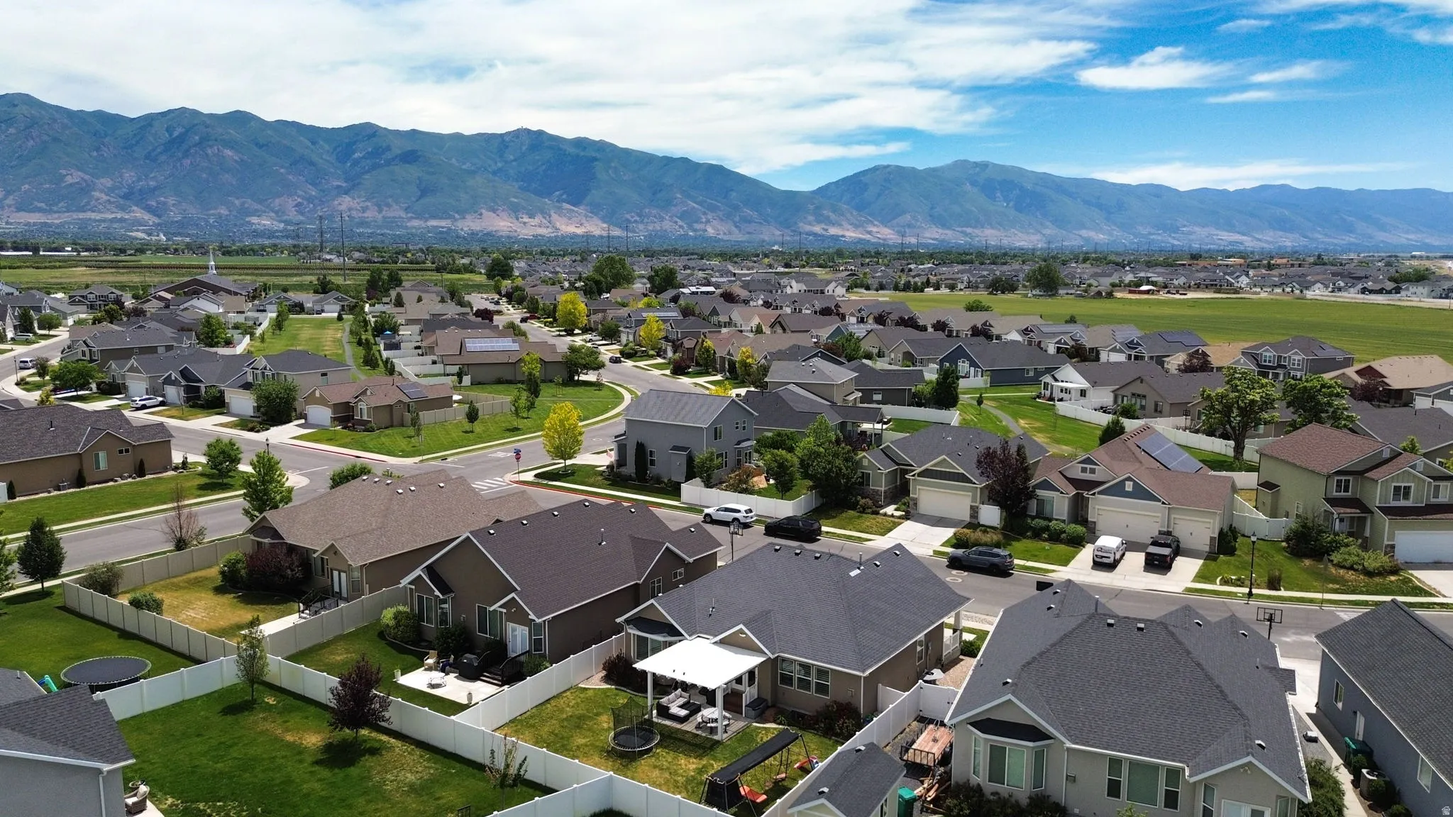 Residential community featuring varied home styles, paved streets, and green spaces, all set against a distant mountain range