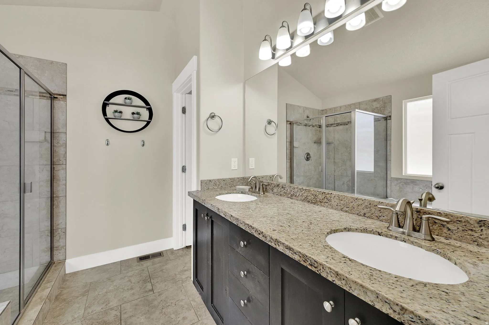 Spacious bathroom featuring a double vanity with stone countertops, undermount sinks, and brushed nickel fixtures