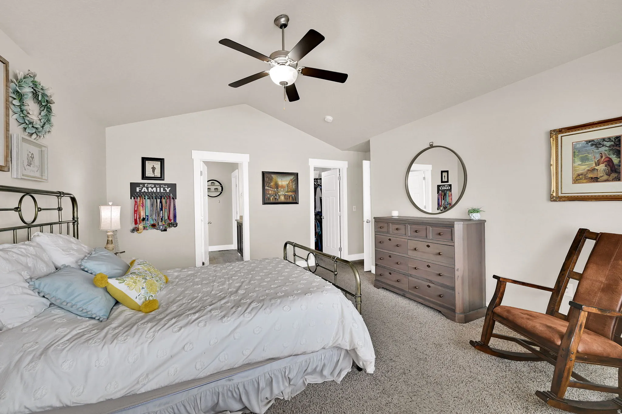 Vaulted ceiling bedroom featuring a ceiling fan with light fixture, neutral carpeting, and white trim