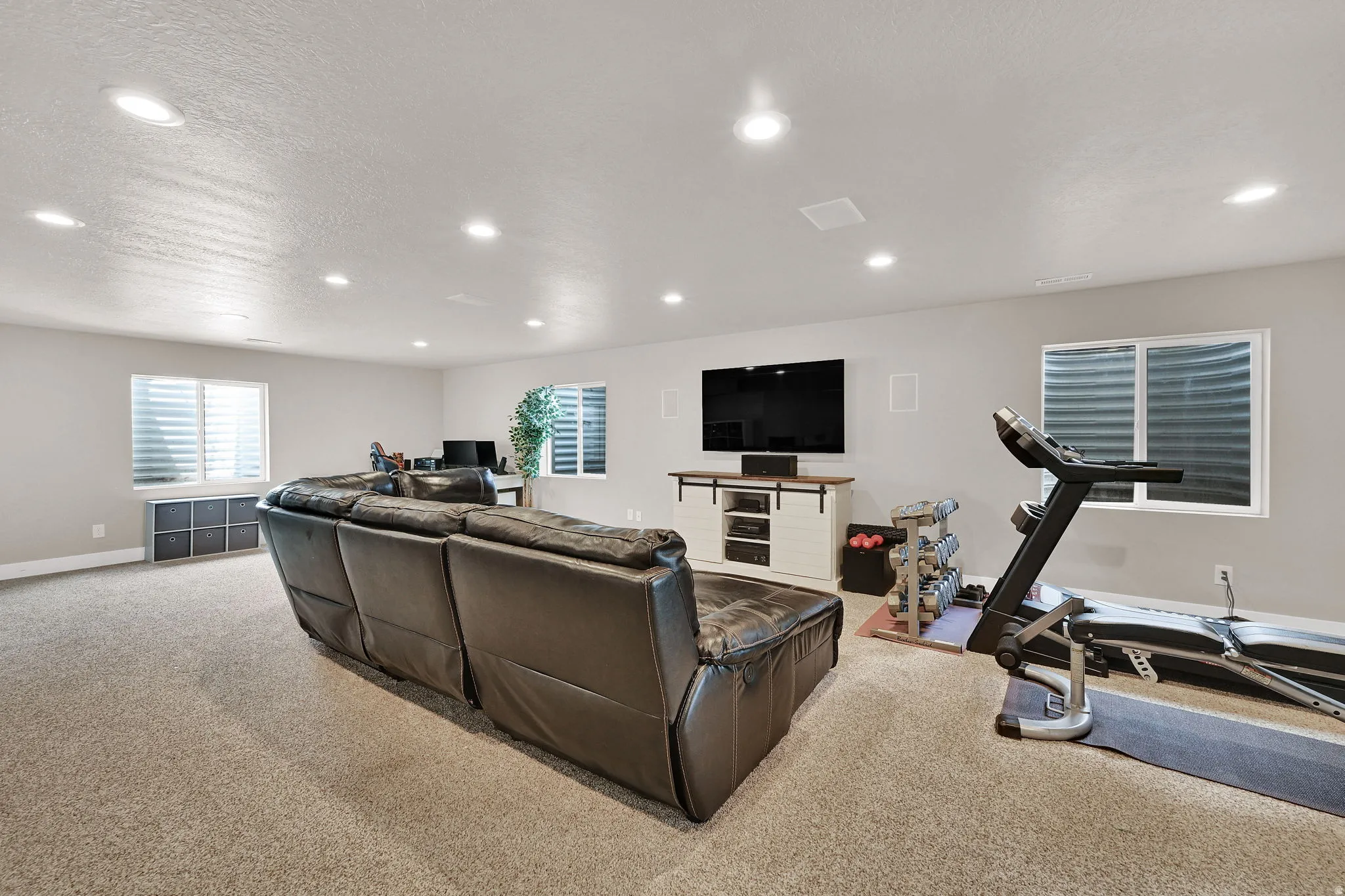 Spacious room featuring light-colored walls, recessed lighting, and carpet flooring