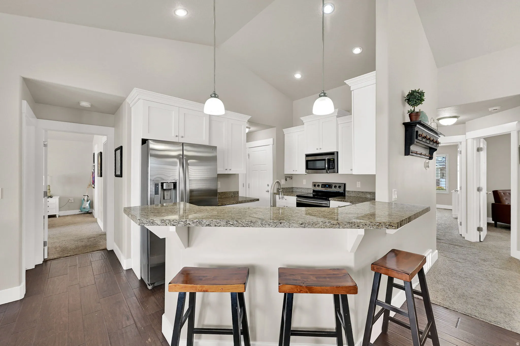 Kitchen featuring white cabinetry, stainless steel appliances, and a breakfast bar with stone countertops